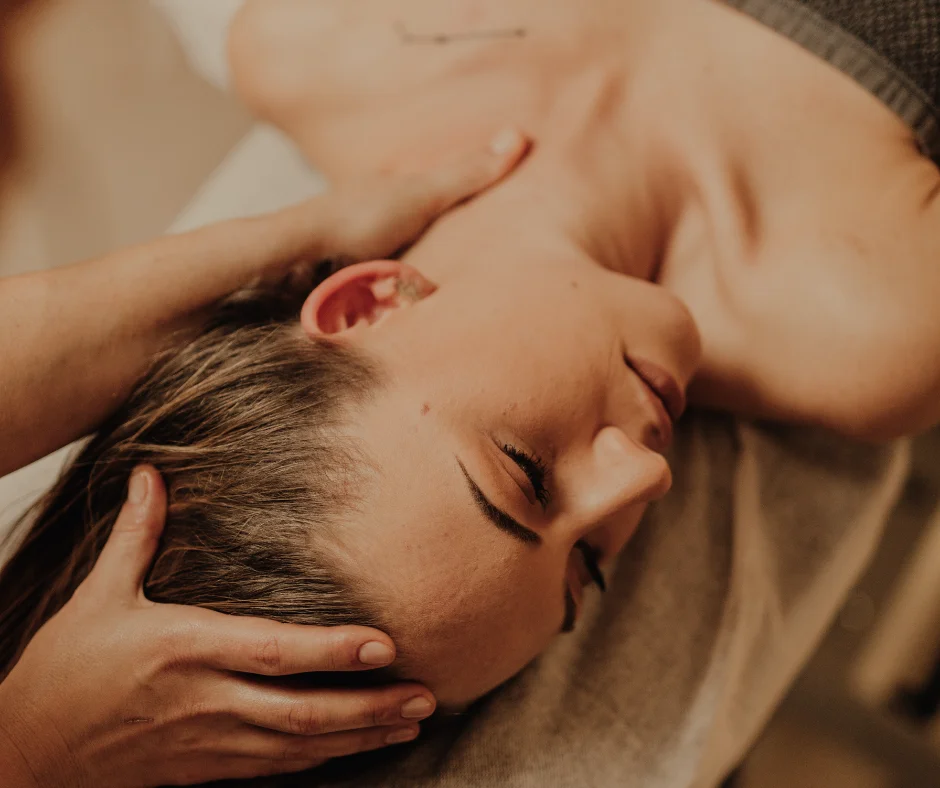 Massage de la tête et de la nuque réalisé sur une femme allongée, les yeux fermés.
